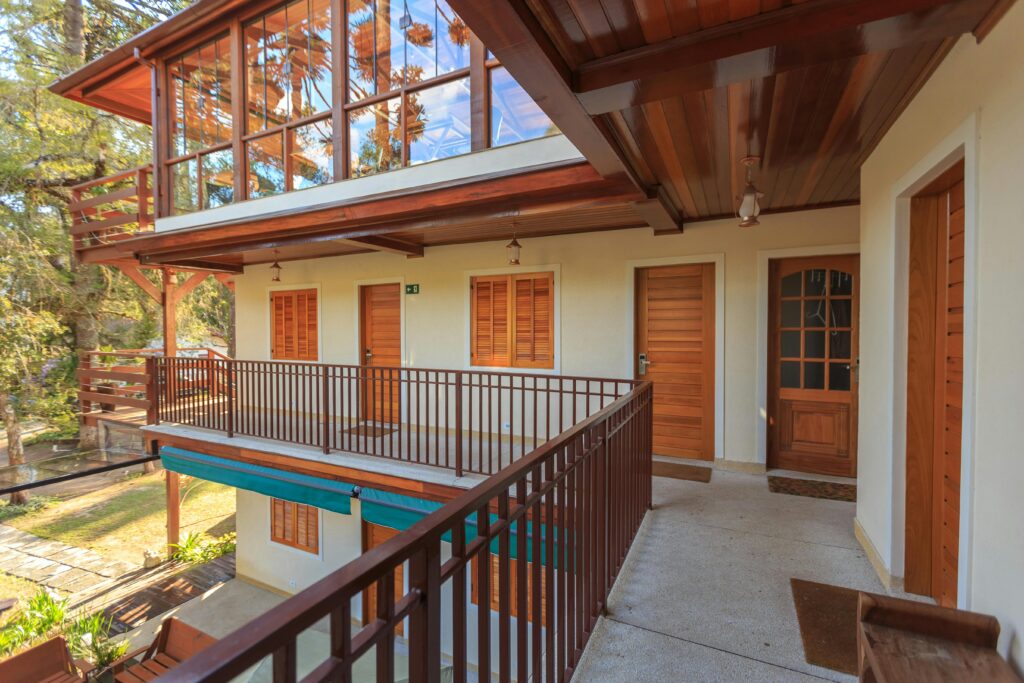 Charming villa exterior with wooden balcony and large windows showcasing natural views.